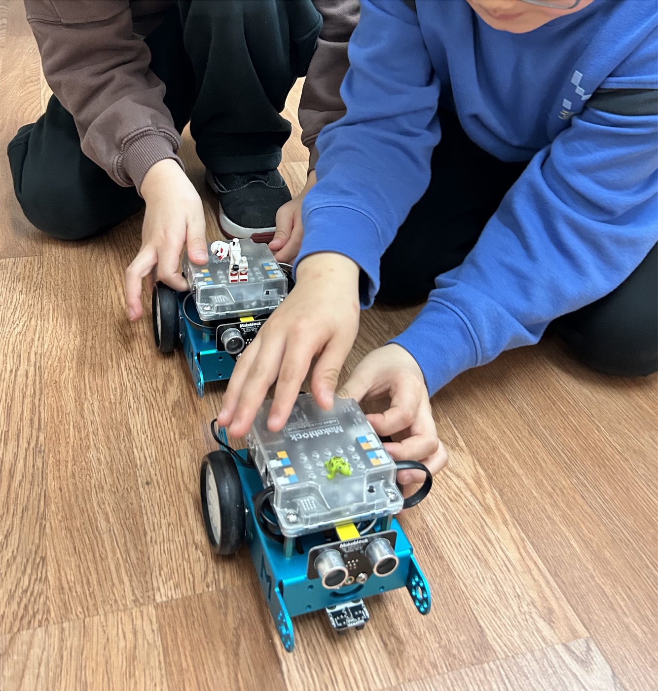 Kids steering small robots across the classroom floor in Robo Rookies